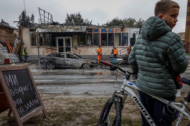 A boy with a bicycle looks on near buildings damaged during a Russian drone and missile strike amid Russia's attack on Ukraine, in the town of Brovary, outside of Kyiv, October 10, 2025. REUTERS/Alina Smutko     TPX IMAGES OF THE DAY