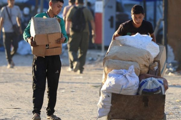 two young boys carry boxes and bags