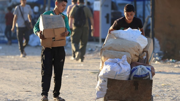 two young boys carry boxes and bags