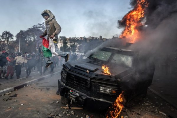 Who is in charge of Madagascar after President Rajoelina flees? A protester holding a Malagasy flag jumps from a vandalised Gendarmerie armoured vehicle