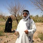 A man holds a bottle of cloudy water in the farm of Iraqi farmer Zuleikha Hashim Taleb