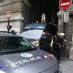 Tourists walk past a French police officer after the Louvre Museum was closed following a robbery, in Paris on October 19, 2025