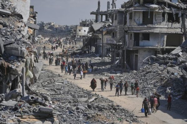 Displaced Palestinians walk with their belongings as they return to their homes in Khan Younis