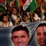 Supporters of Rodrigo Paz wave flags and hold up a banner with his face and his running mate's.