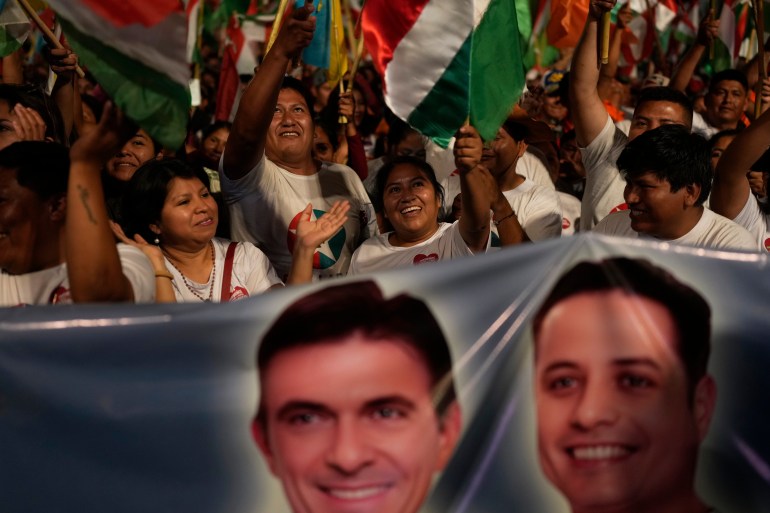 Supporters of Rodrigo Paz wave flags and hold up a banner with his face and his running mate's.