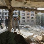 Residents remove debris from a house damaged by attacks.