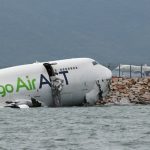 A cargo plane lies partially in the sea after veering off the runway during landing at Hong Kong International Airport