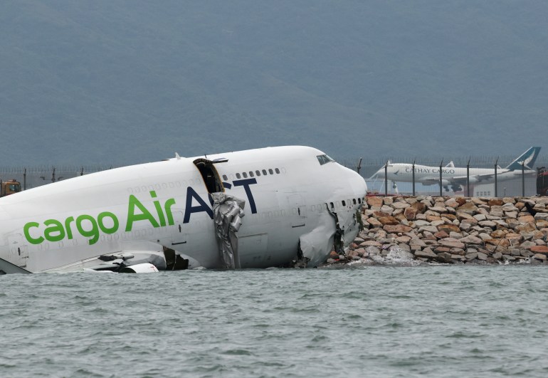 A cargo plane lies partially in the sea after veering off the runway during landing at Hong Kong International Airport