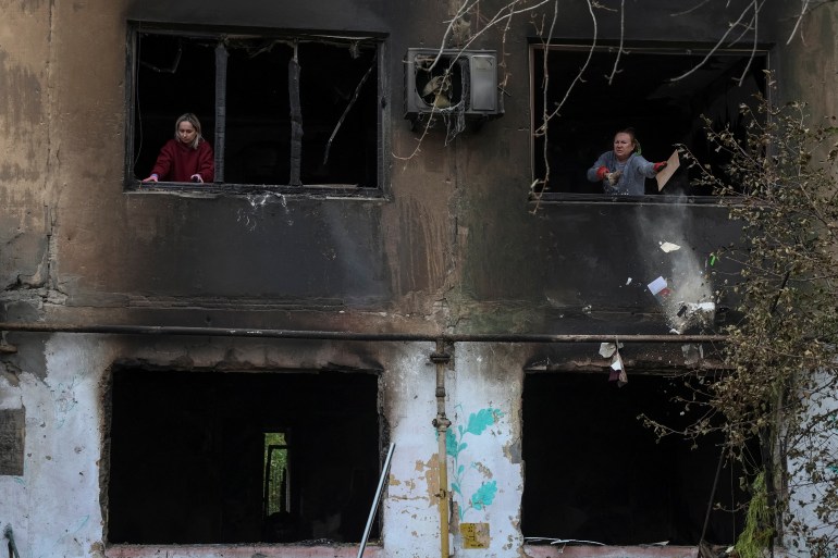 Residents remove broken glass from windows of an apartment building damaged by a Russian drone strike, amid Russia's attack on Ukraine, in the town of Shakhtarske in Dnipropetrovsk region, Ukraine October 19, 2025. REUTERS/Anatolii Stepanov