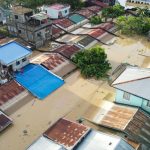 Residents stand on the roof of their flooded house in Ilagan City, Isabela province, north of Manila on November 11, 2025, as flood waters continue to inundate homes due to heavy rains brought about by Super Typhoon Fung-wong.