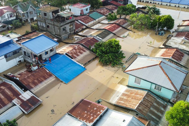 Residents stand on the roof of their flooded house in Ilagan City, Isabela province, north of Manila on November 11, 2025, as flood waters continue to inundate homes due to heavy rains brought about by Super Typhoon Fung-wong.