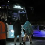 Two people walk towards a bus