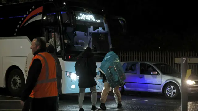 Two people walk towards a bus