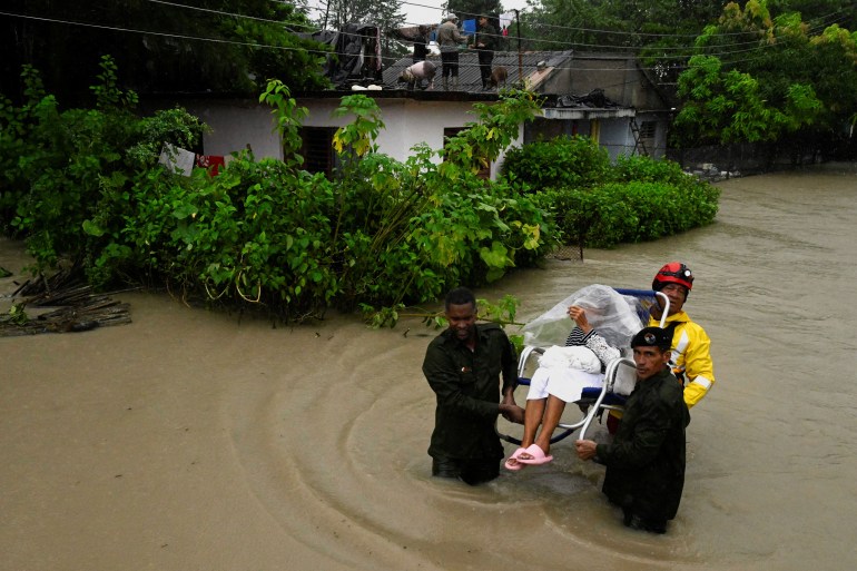 A woman is evacuated from her home by emergency personnel after the Cauto River flooded due to Hurricane Melissa, in Rio Cauto, Granma Province, Cuba October 31, 2025. REUTERS/Norlys Perez